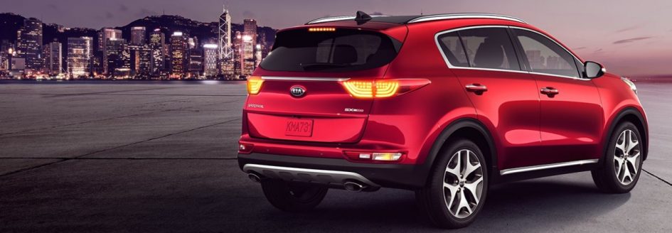 A red 2019 Kia Sportage parked in front of a city skyline