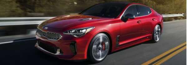 Red 2019 Kia Stinger driving along a highway.
